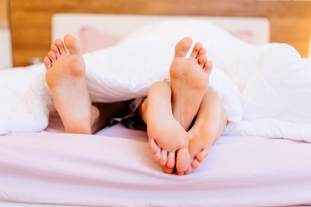 Couple having sex under blanket with their feet visible. (Foto: banco de imagens)